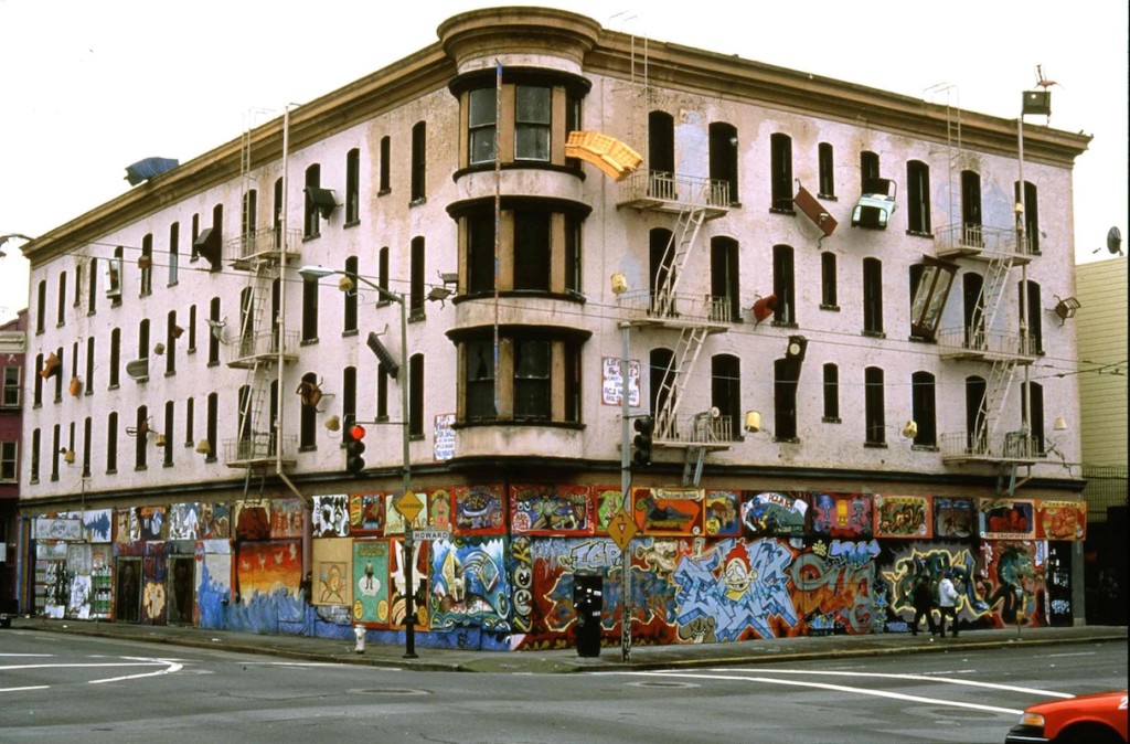 Defenestration. Against society’s expectations, these everyday objects flood out of windows like escapees, out onto available ledges, up and down the walls, onto the fire escapes and off the roof. San Francisco, California. 1997. Multi-disciplinary sculptural mural by Brian Goggin.